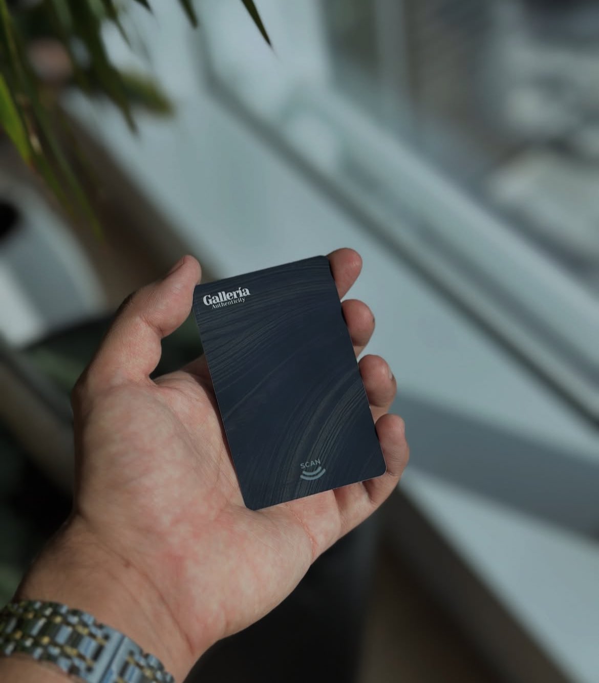 A hand holding the black Gallería card: brushed texture, wordmark, and a SCAN mark with contactless arcs